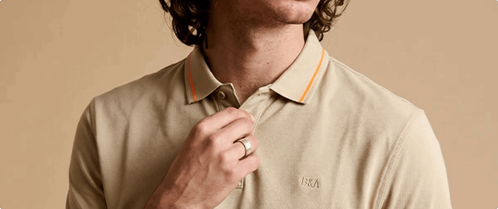 Dettaglio di una polo beige indossata da un modello.