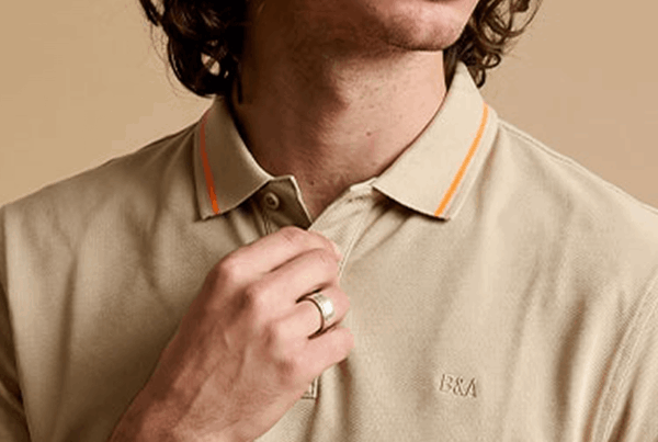 Dettaglio di una polo beige indossata da un modello.